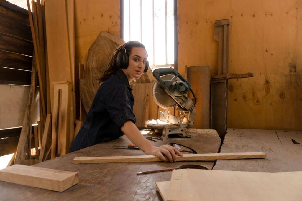 Eine junge Frau arbeitet mit Holz. Sie konzentriert sich auf ihr Kerngeschäft und hat keine Zeit für Marketing im Handwerk.