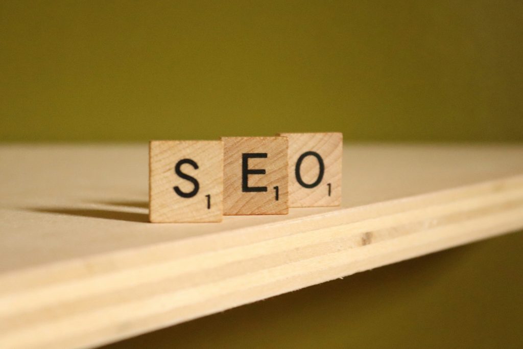 Auf einem Regal stehen drei Holzbuchstaben, die das Akronym SEO bilden. 